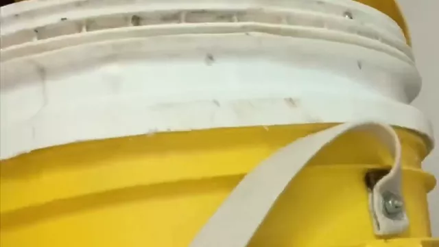 Balde blanco encastrado arriba de un balde amarillo, con la correa de tela para llevarlo